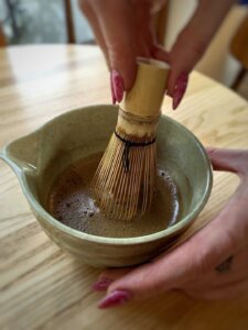 baristka miesza hojiche miotełką w miseczce