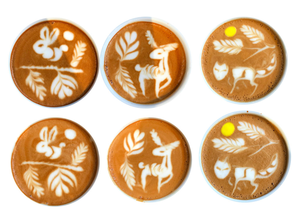 Trzy filiżanki z zaawansowanym latte art - jeleń, lis i królik na powierzchni kawy