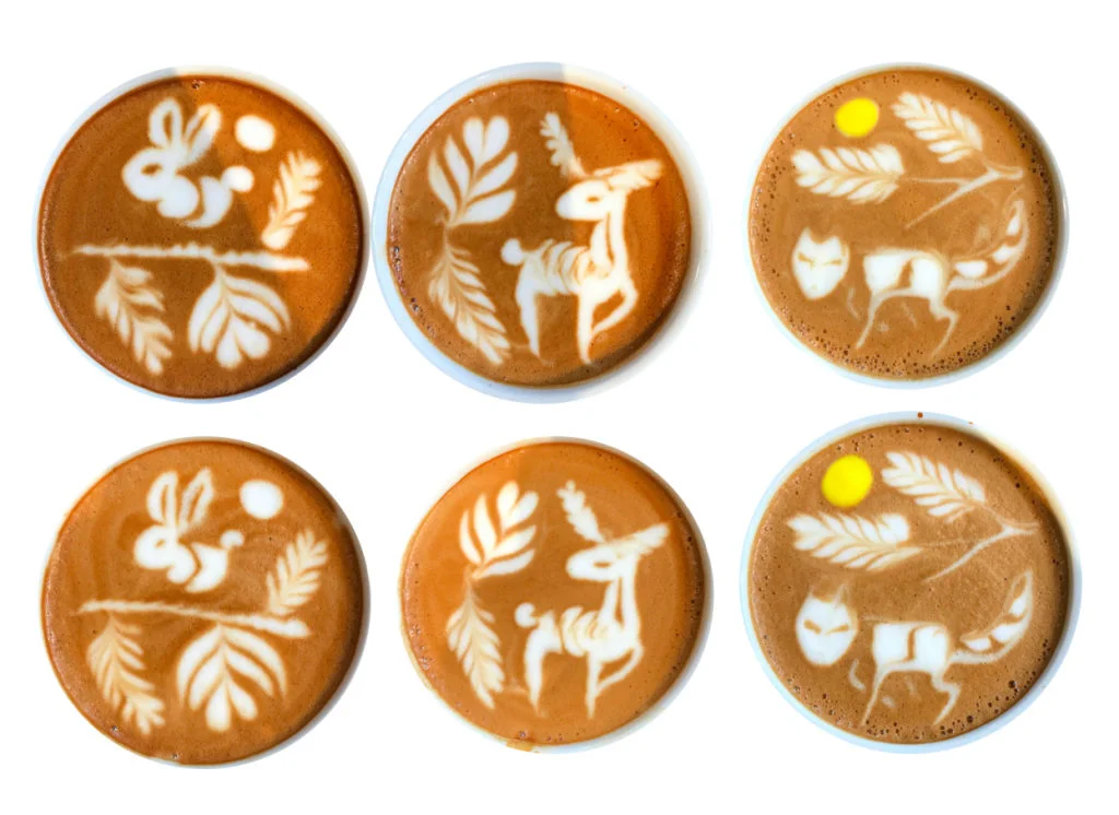 Trzy filiżanki z zaawansowanym latte art - jeleń, lis i królik na powierzchni kawy