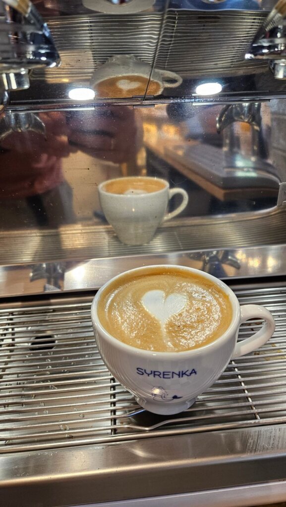 Cappuccino z sercem z mleka w filiżance z logo Syrenka