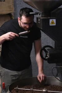 Palacz Colbergcoffee wącha próbkę kawy pobraną próbnikiem z pieca podczas palenia