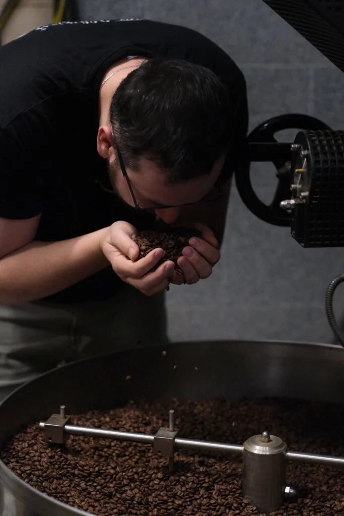 Palacz Colbergcoffee wącha świeżo paloną kawę w dłoniach nad chłodnicą pieca